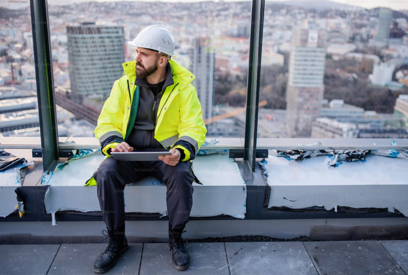 Byggarbetare i reflexjacka på tak med surfplatta..jpg